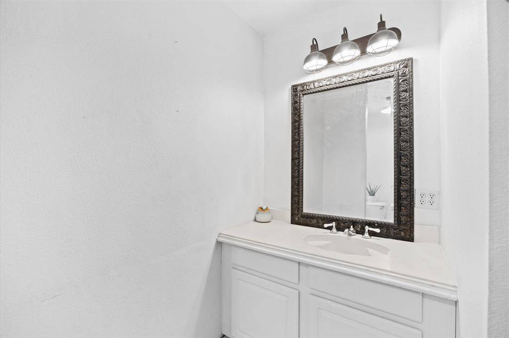 Elegant bathroom vanity with a white countertop, framed mirror, and modern three-light fixture.