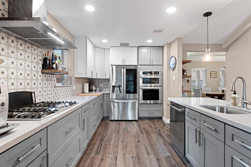 Completely remodeled kitchen featuring built-in shelves, a gas stove, and sleek stainless steel appliances, offering both functionality and style.