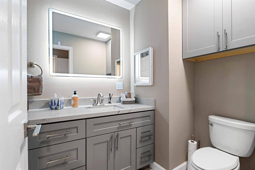 Bathroom featuring an upgraded vanity and a stylish backlit mirror for enhanced illumination and modern appeal.