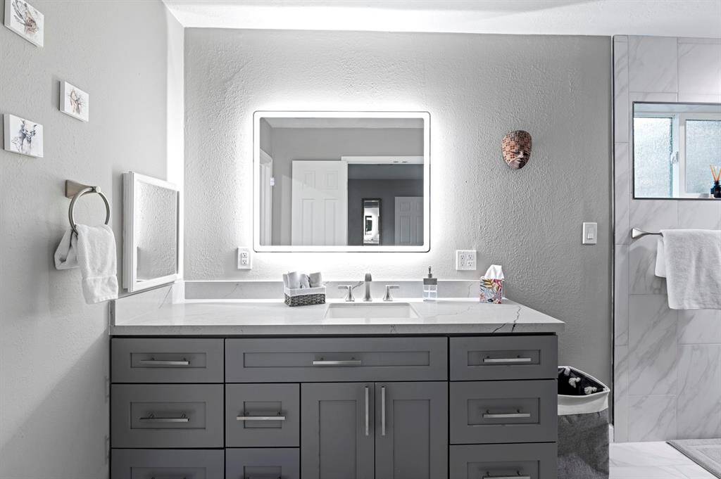 Primary master suite featuring a long vanity and a backlit mirror, combining elegance with modern functionality.