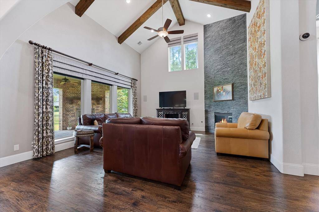 Living room with cathedral beamed ceiling, corner fireplace and views to the backyard