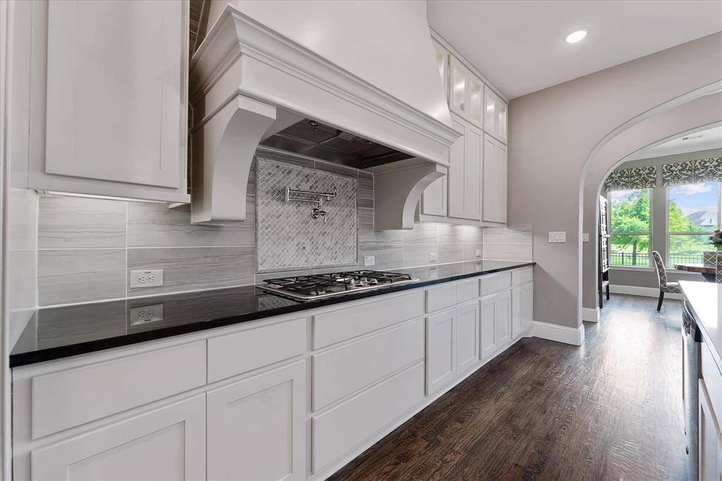 Gas cooktop, accent backsplash with pot filler and custom range hood