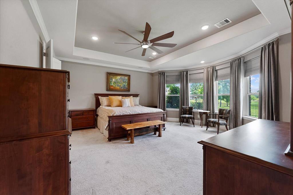 Private primary suite with tray ceiling and bay windows, seating area, recessed lighting.