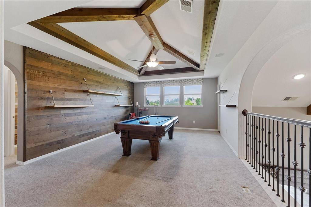Gameroom with accent wall and beamed ceiling