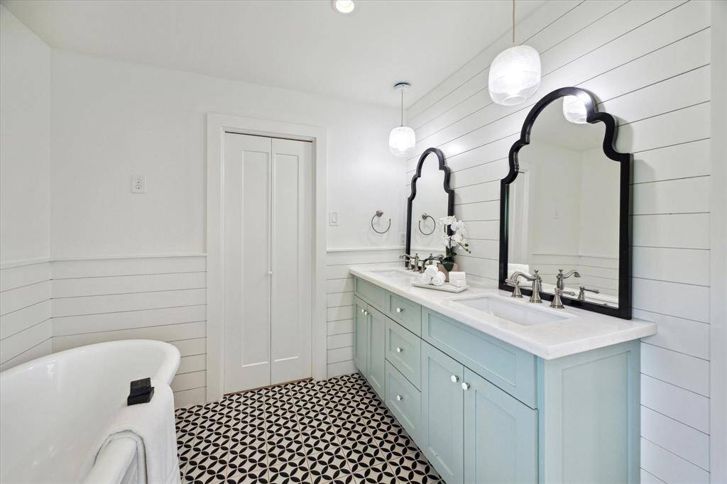 Another view of the ensuite bath highlights the double sinks, stylish pendant lighting, and doors that lead to the walk-in closet.