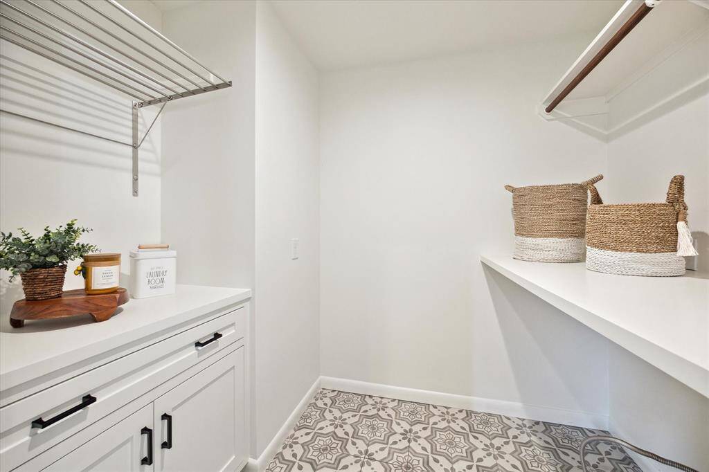 This stylish laundry room features storage and a convenient hanging bar, making everyday chores feel a bit more enjoyable in a beautifully functional space.