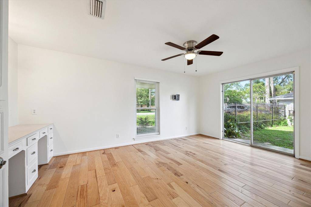 Spacious third bedroom with views of the yard, walk-in closet, ceiling fan with light and a built-in desk.
