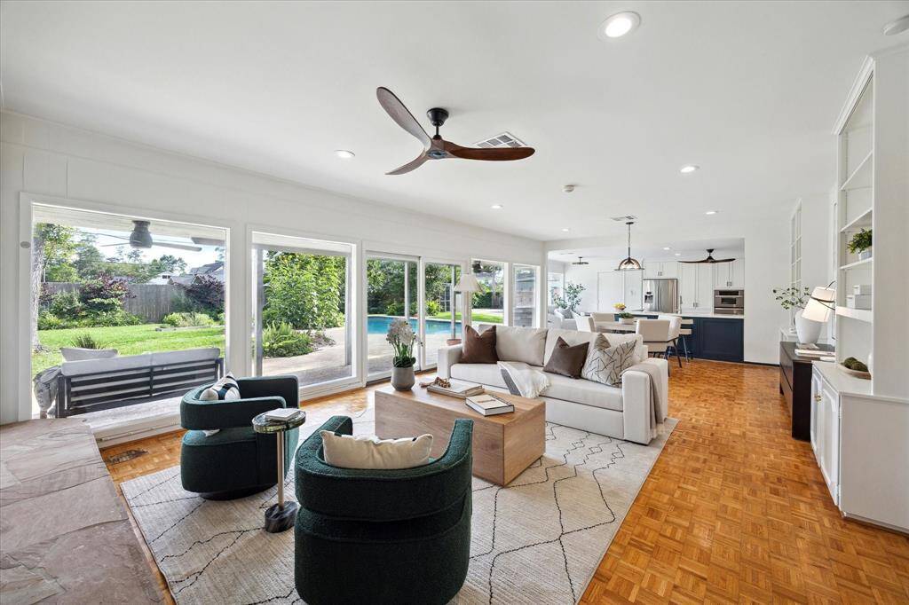 Spacious living room with wood parquet floors and floor-to-ceiling windows overlooking the backyard.