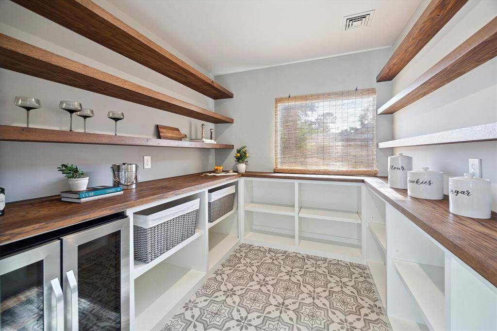 Amazing working pantry featuring warm wood countertops and open shelving. This beautifully designed space will make all your organizational dreams come true!