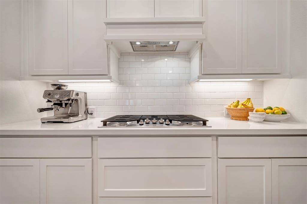 Close up view of the gas cooktop and custom tile backsplash.