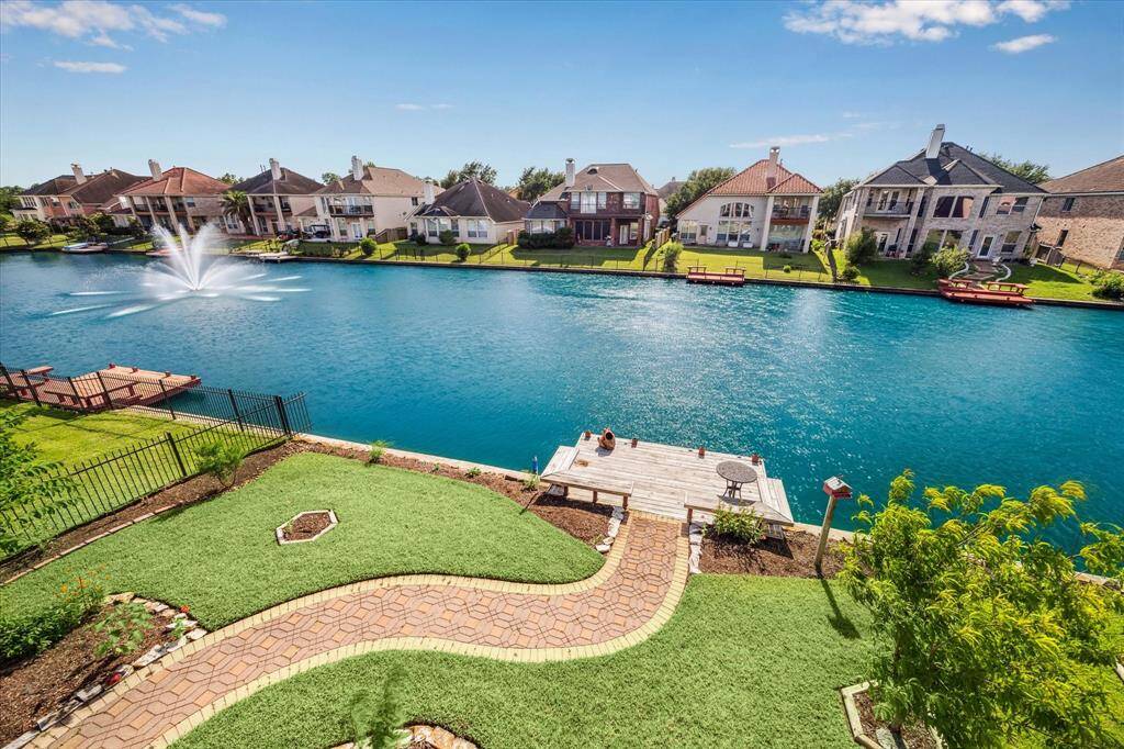 A manicured backyard with flowerbeds and paver lined walkway to your private dock.