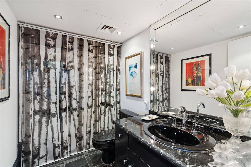 Guest bathroom with granite counters, stone floors and tub/shower combination.