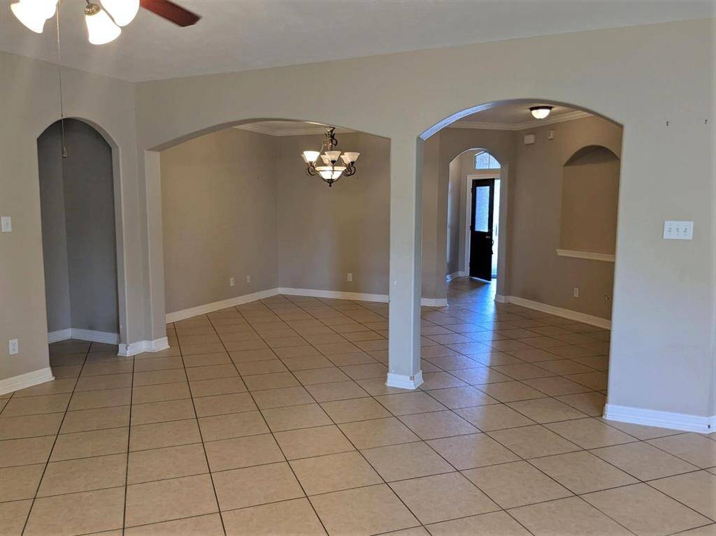 Spacious dining area with elegant arched entryways and warm lighting, perfect for gatherings.