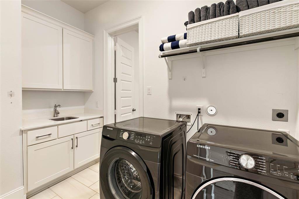Laundry room located downstairs with upper cabinetry, a countertop for folding, and plenty of space to stay organized.