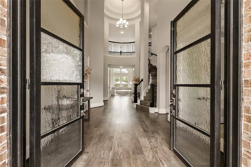 The grand foyer with soaring ceilings, impressive tiered rotunda, wrought iron curved staircase and elegant entry lighting set the tone for this exquisite home.
