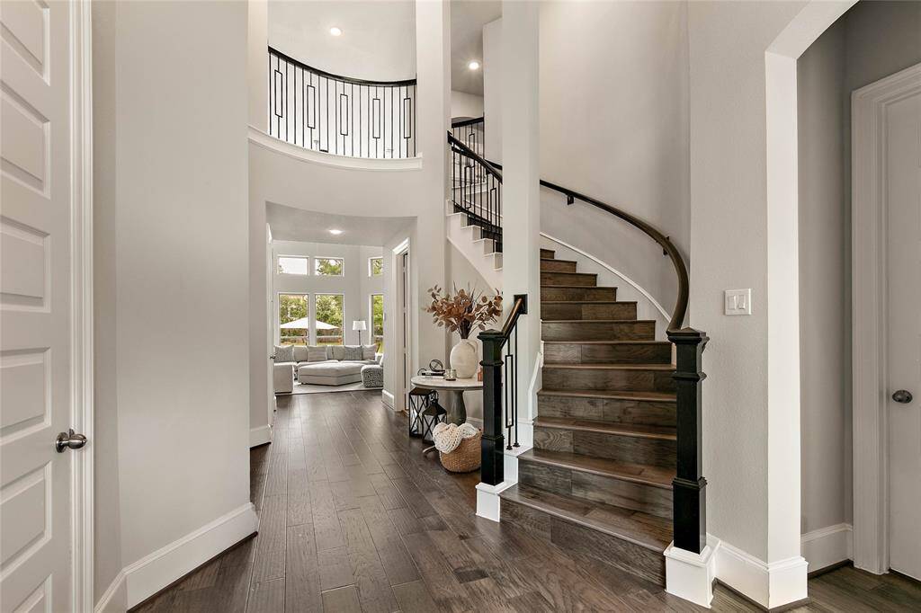 Beautifully designed staircase with dark wood handrails and wrought iron spindles add a stylish transition to the second floor.