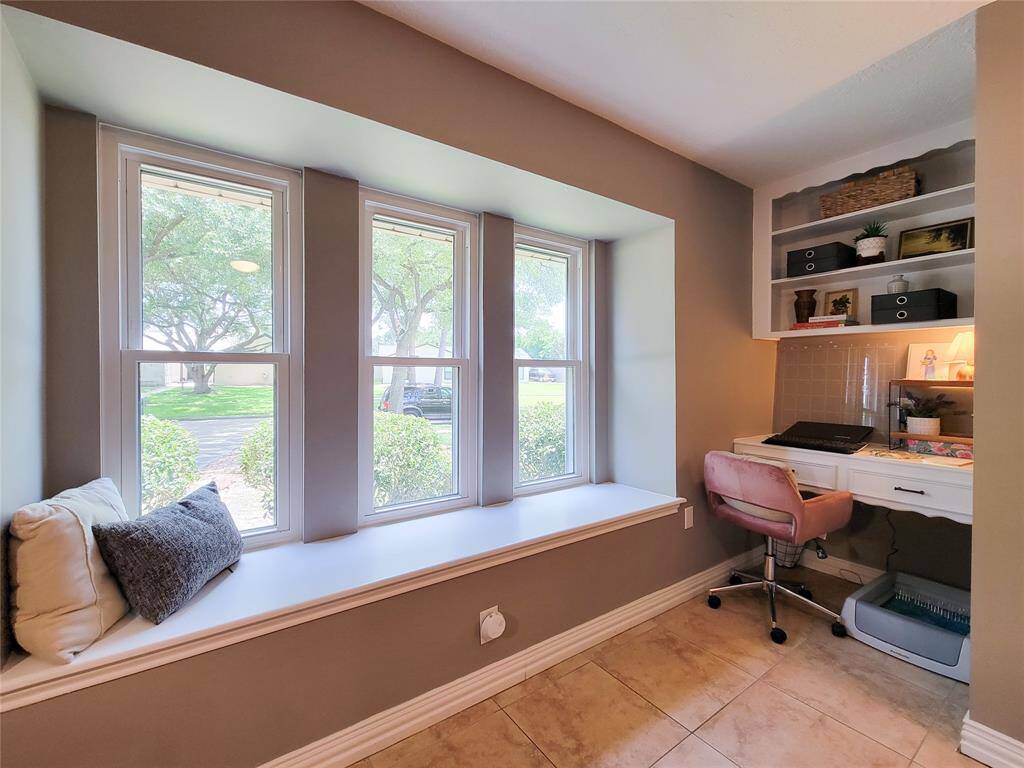 This same space also features a built-in desk with shelving, ample natural light from large windows, and a comfortable bench seat perfect for reading or relaxation.