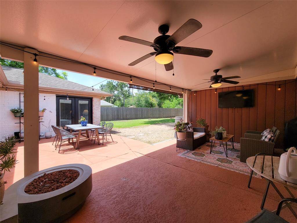 This photo is open to a sunny backyard with a dining area and offers a relaxed, entertainment-friendly atmosphere.