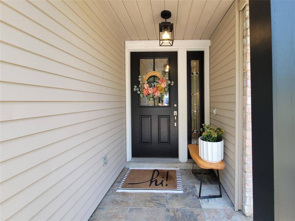 Welcoming entryway with a black front door featuring a floral wreath. The space is accented by a stylish lantern light, offering a cozy and inviting atmosphere.