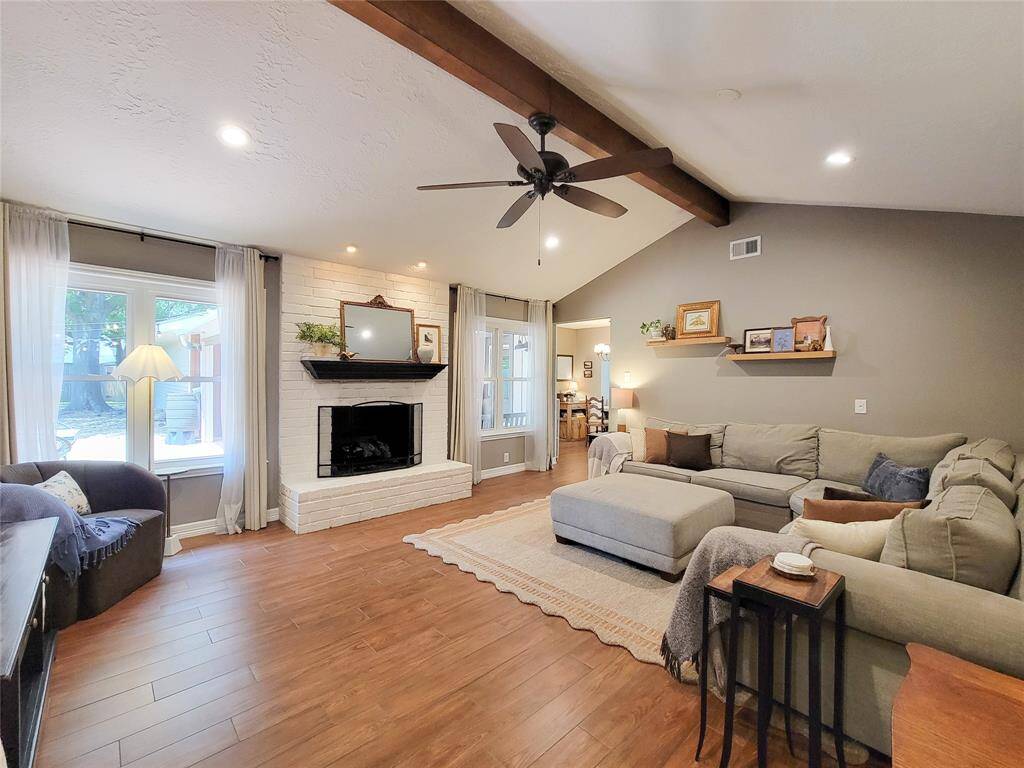 This inviting living room features a cozy white brick fireplace, and ample natural light, creating a warm and welcoming atmosphere.