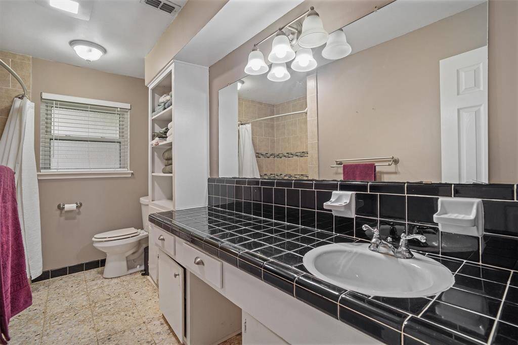 Second full bath with additional counter space, tiled shower, and storage