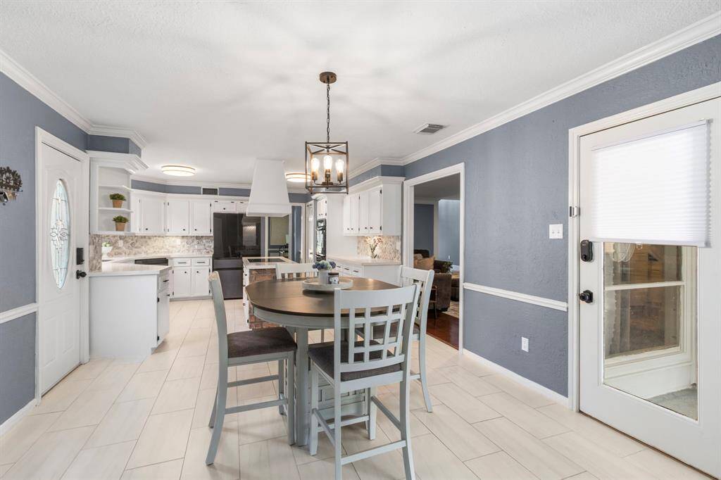 If "Large Kitchen" is on your must-haves list, you can check that box now! The door to the left leads out to the driveway for easy grocery unloading. Updated lighting with a nod to classic design work perfectly in this space. The door to the right leads out to the enclosed patio, ideal for indoor-putdoor entertaining.