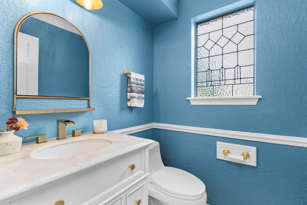 The downstairs powder room features updated, mirror, fixtures and vanity. The decorative window is textured glass, allowing this space to be flooded with natural light without sacrificing privacy.