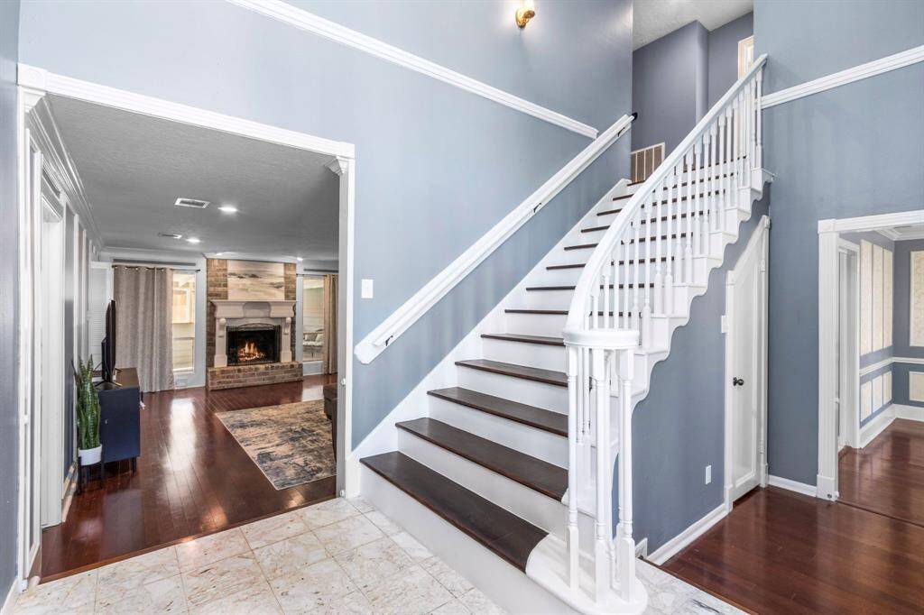 As you enter the home, the two-story entry opens up to welcome you home. This is the first of two stairways in the home. Views through to the living room and and back patio and to the dining room at the right. Don't miss the storage under the stairs!