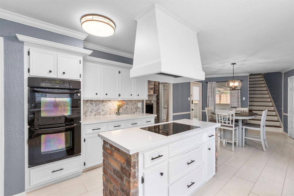 From the kitchen island with drawer and cabinet storage, you have views to the living room, breakfast room, and to the wooden-treaded stairs leading upstairs to game room. Under cabinet lighting was added for aesthetics and functionality.