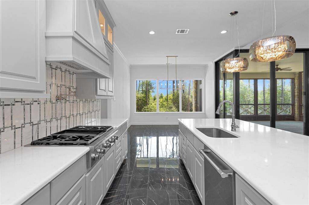 Enjoy forest views while cooking or entertaining in this stunning kitchen, where designer finishes meet natural light and indoor-outdoor harmony through walls of windows and glass doors.