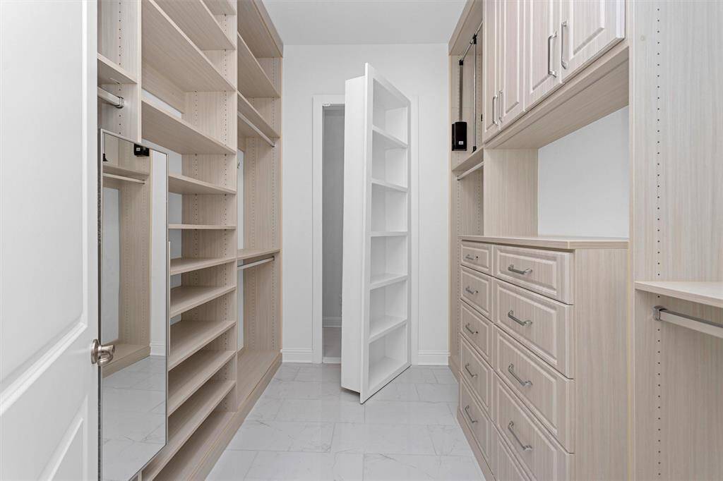 The custom walk-in closets offers abundant built-in storage, soft-close drawers, and a hidden safe room concealed behind a clever bookshelf door for ultimate peace of mind.