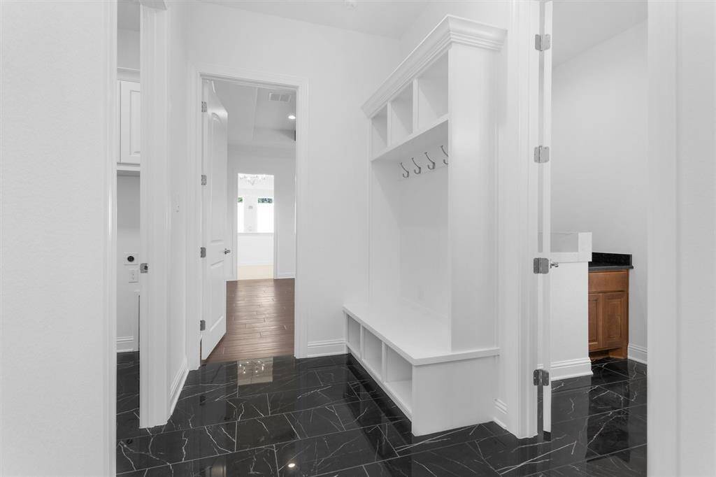 This well-appointed mudroom features built-in storage with hooks and cubbies, offering a stylish and functional landing zone just off the home’s secondary entry. Utility room and pet washing station on either side.