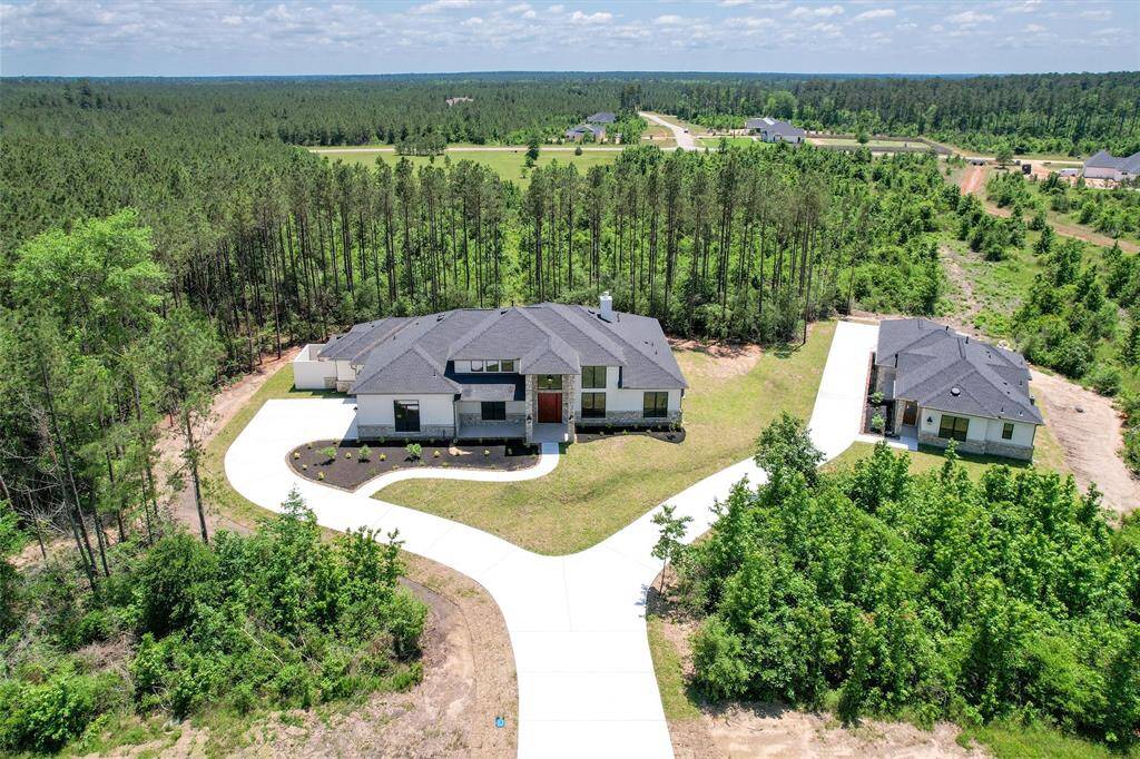Republic Grand Ranch wooded estate featuring a newly built main home and separate guest home, both surrounded by forested privacy and connected by winding driveways.