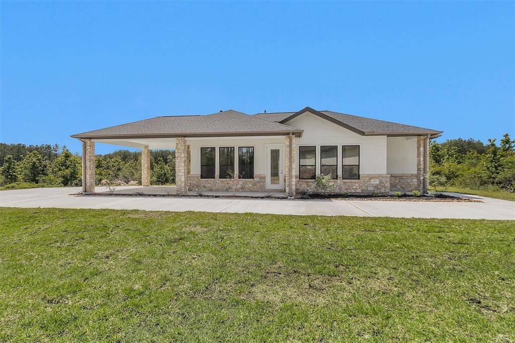 The separate 2-bedroom, 2-bath guest home features a charming stone-accented exterior, full kitchen, carport, and covered porch—perfect for multigenerational living or long-term guests.