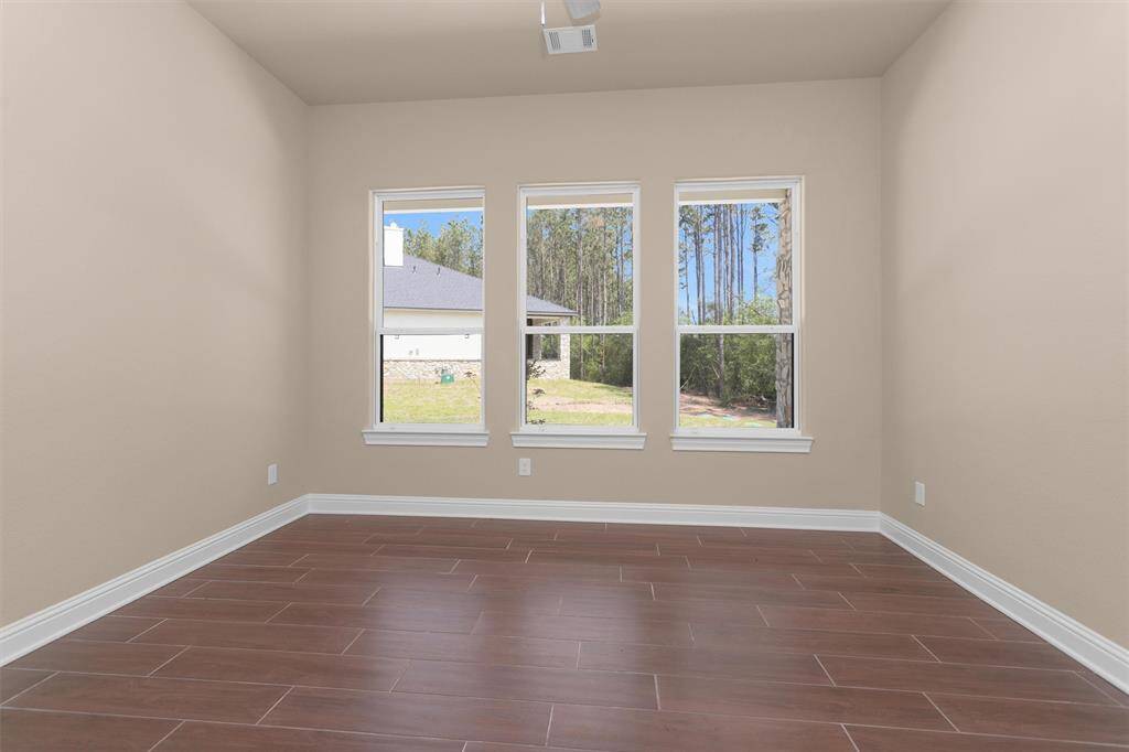 The second bedroom in the guest house features three large windows that bring in tons of natural light and wood-look tile flooring.