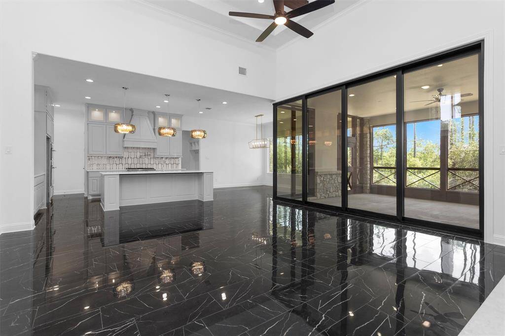 This expansive great room flows effortlessly into the designer kitchen with chic black tile flooring complemented by light cabinetry and finishes.