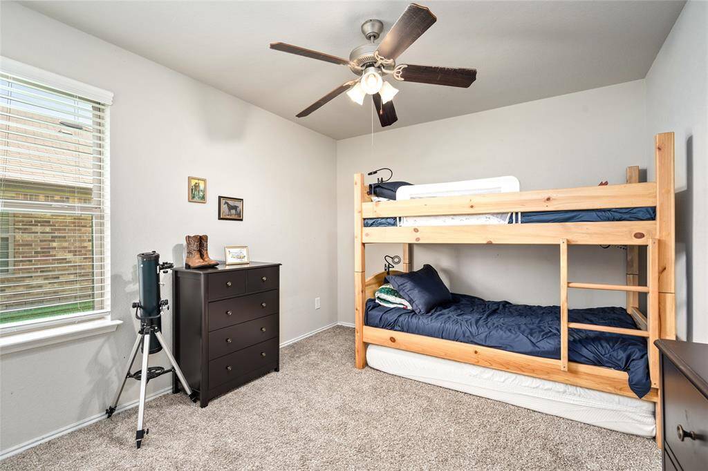 This secondary bedroom offers a comfortable and functional layout with ample natural light from the window. Its neutral tones and soft carpeting provide a versatile backdrop, making it ideal for use as a guest room, home office, or personal space.