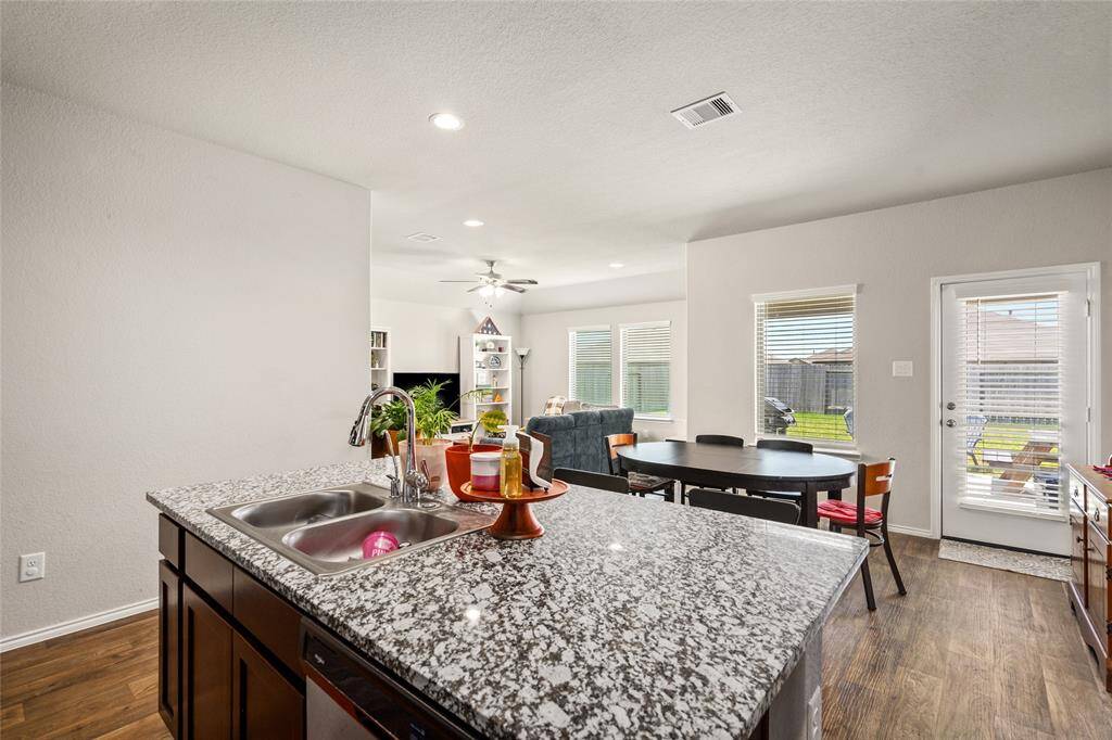 This view from the kitchen highlights the seamless flow into the dining and living areas, creating an open-concept layout ideal for entertaining or everyday living. Ample windows and a glass door bring in abundant natural light, with easy access to the backyard for indoor-outdoor enjoyment.