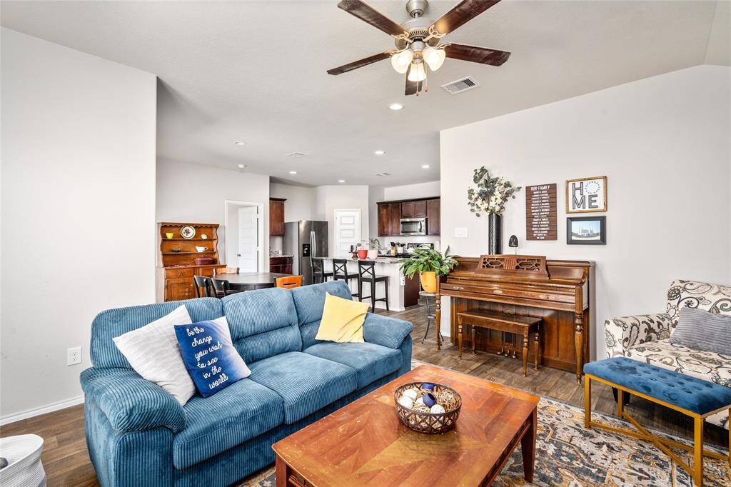 Step into a beautifully integrated living, dining, and kitchen area designed for effortless entertaining and everyday comfort. The spacious living room features a vaulted ceiling, abundant natural light, and elegant built-ins that frame a cozy media nook. A blend of plush seating, warm wood accents, and stylish décor makes it both inviting and functional.