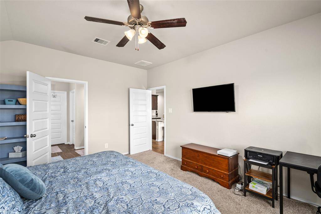 This inviting primary bedroom features a large, open layout with room to comfortably accommodate a king-sized bed and additional furniture. Three oversized windows allow abundant natural light to stream in, while offering a peaceful view of the backyard. The room boasts plush wall-to-wall carpeting and a vaulted ceiling that enhances the sense of space and airiness.Neutral paint tones provide a versatile canvas for any design style, while a ceiling fan with light fixture adds comfort and functionality.