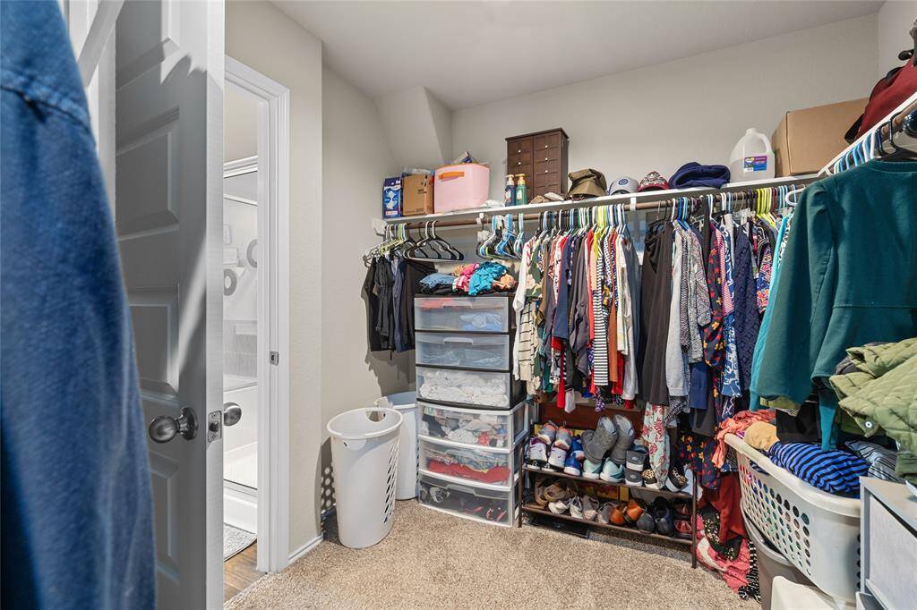 Spacious walk-in closet featuring built-in shelving and ample hanging space, conveniently located with direct access to the en-suite bathroom.
