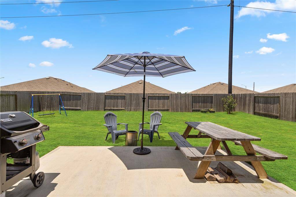 Step into a generously sized backyard perfect for both relaxation and entertaining. The extended concrete patio features a built-in grill, picnic table, and Adirondack seating under a large umbrella—ideal for weekend barbecues or quiet mornings with coffee. A lush, fully fenced lawn provides ample space for kids, pets, or gardening, while the swing set adds a playful touch for families. This outdoor haven is your private slice of sunshine.