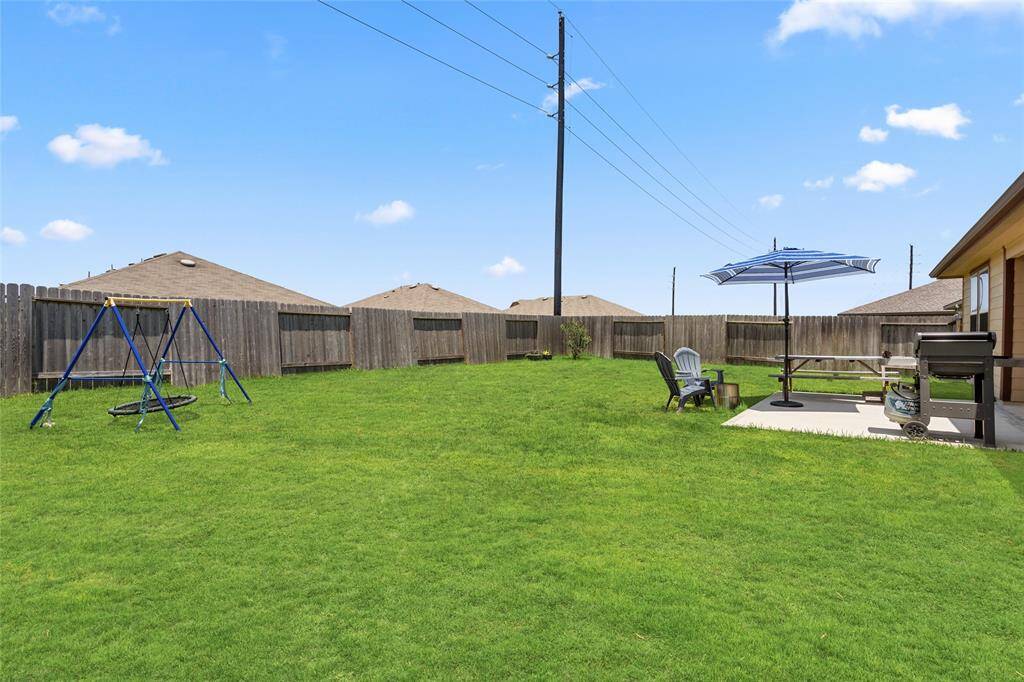 This expansive backyard offers a perfect mix of leisure and play—with a swing set for the kids and a patio setup ideal for weekend barbecues or peaceful evenings by the fire pit.
