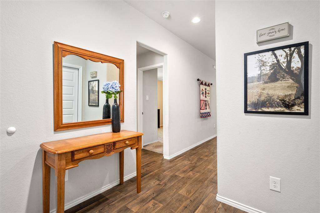 Bright and inviting hallway with recessed lighting and durable wood-look flooring that flows throughout the main living areas. Stylish wall décor and soft neutral tones create a warm, welcoming transition between bedrooms and living spaces. Perfectly positioned for easy access to secondary bedrooms and guest bath.