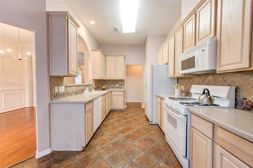 Charming kitchen with corian countertops and tile backsplash. New brush nickel faucet and white porcelain sink.