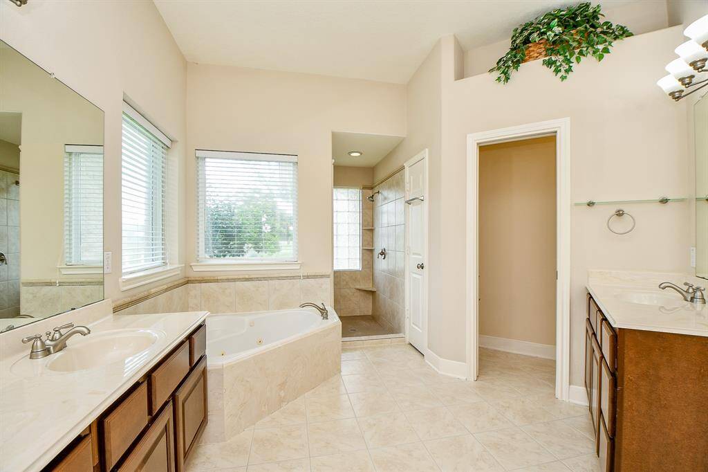 Primary bath en suite with jetted tub, walk in shower, and separate sinks