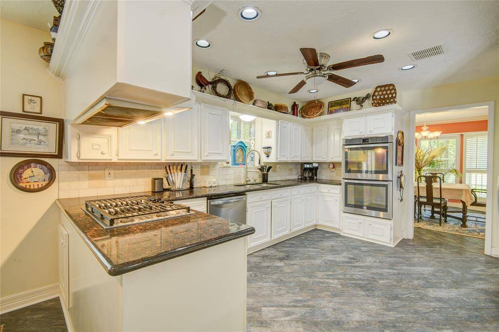 This refined cooktop area features generous granite countertops, a sophisticated double oven, and a graceful sightline into the formal dining room, perfect for effortless entertaining.