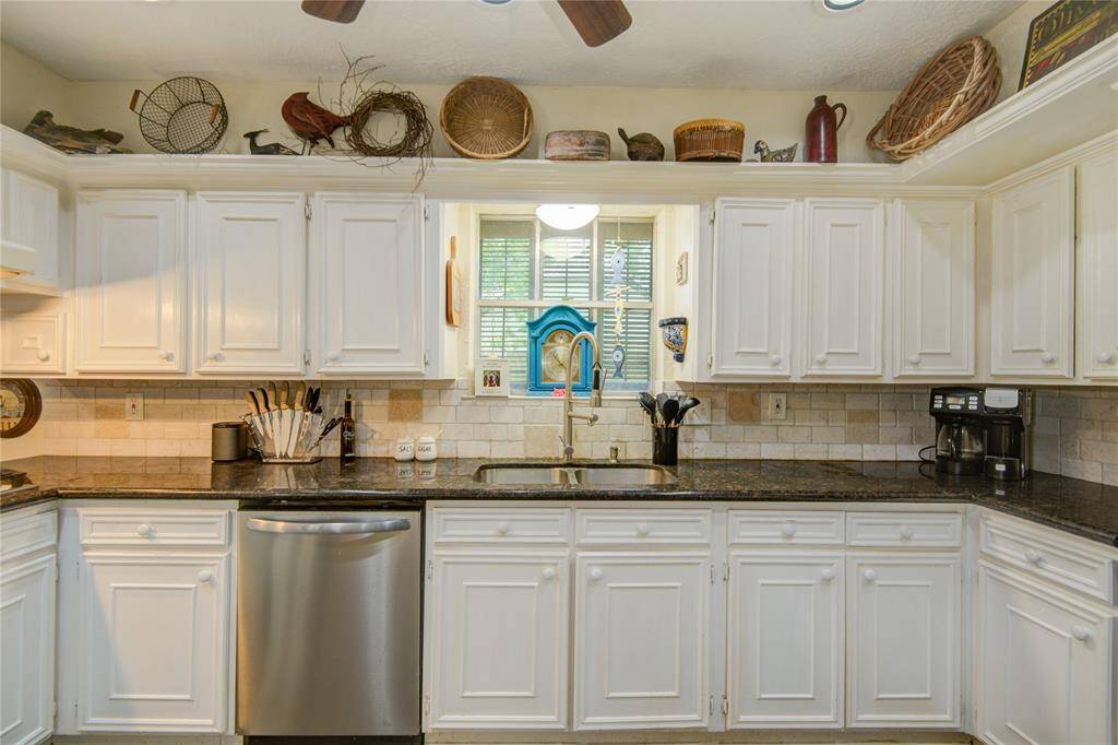 This streamlined view highlights the sink and dishwasher area, complemented by an abundance of custom cabinetry offering ample storage throughout the kitchen.