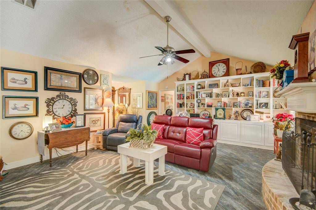 The family room features a striking curved fireplace surround, soaring vaulted ceiling, and an entire wall of built-ins with lower cabinets and open shelving for stylish storage.