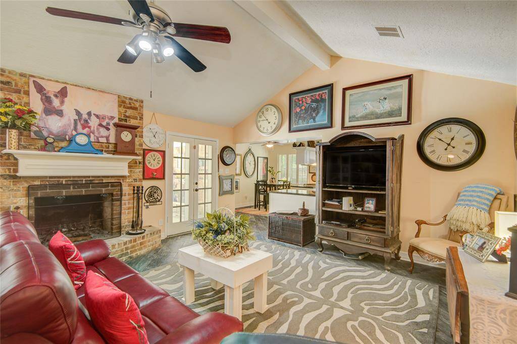 This view of the family room looks back toward the breakfast area, with the elegant curved fireplace on the left and French doors on the right opening to the pool and patio for effortless indoor-outdoor living.